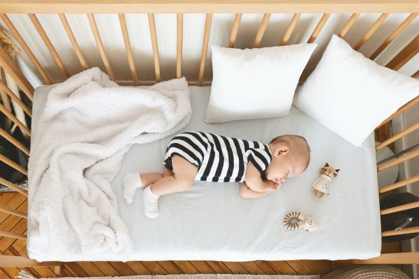 Cute infant baby napping on his side in wooden cot